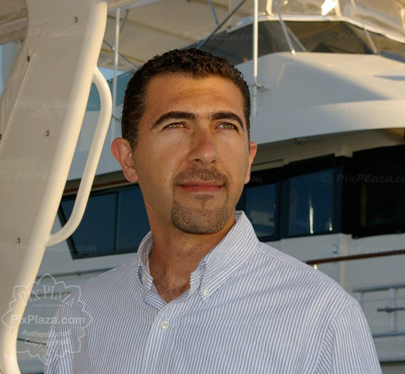 Male model posing in front of a yacht