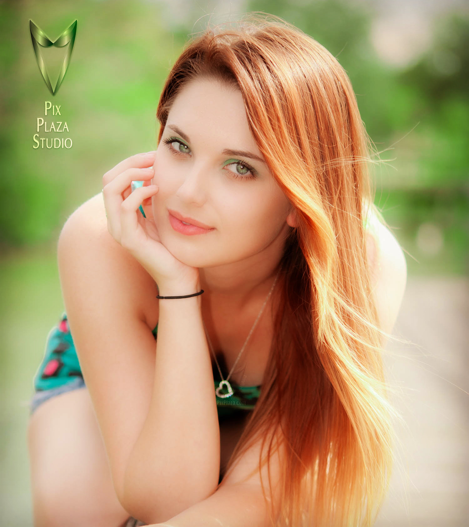 Beautiful young girl with ginger red hair and green eyes posing leaning forward on fence